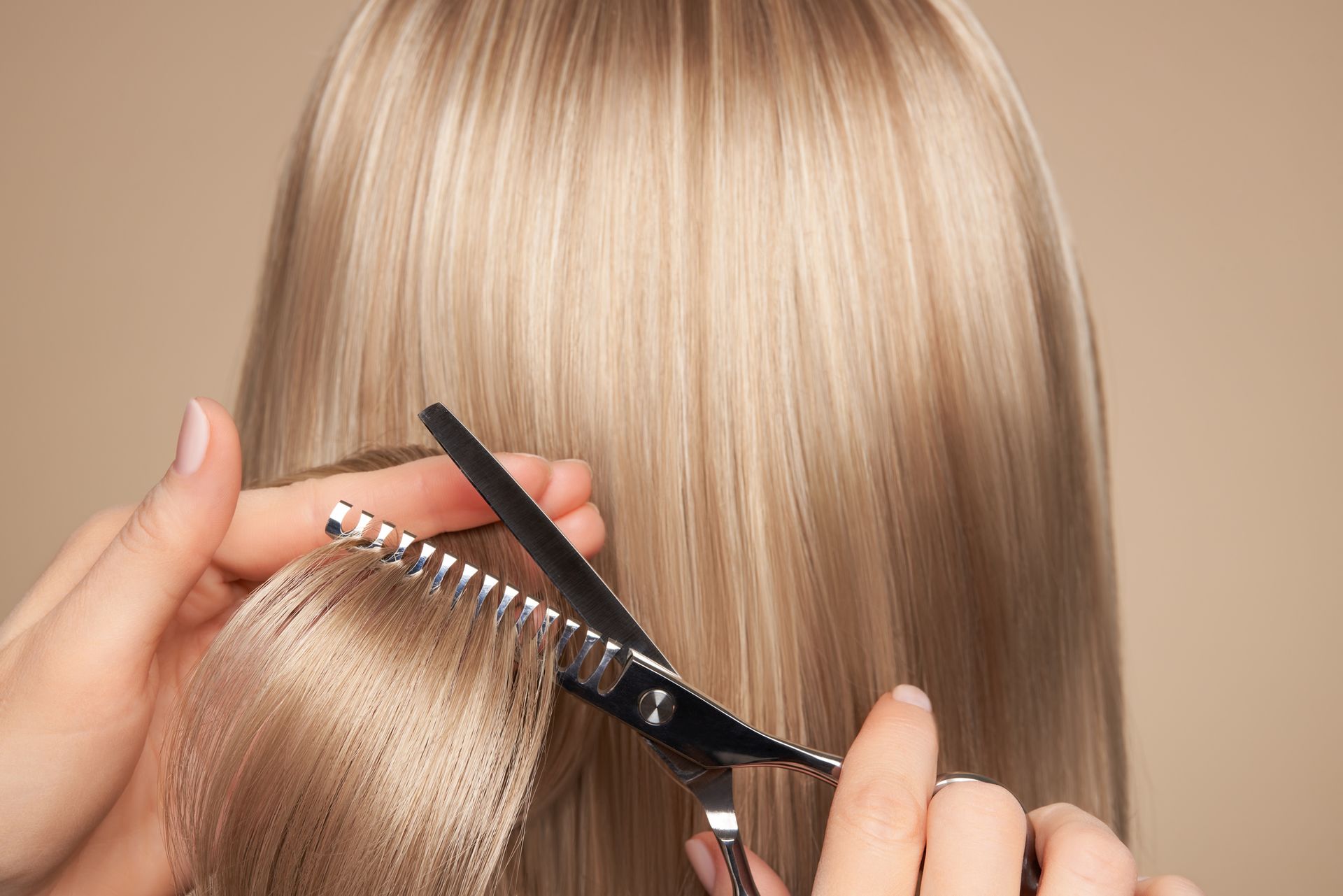 A woman is getting her hair cut by a hairdresser with scissors.