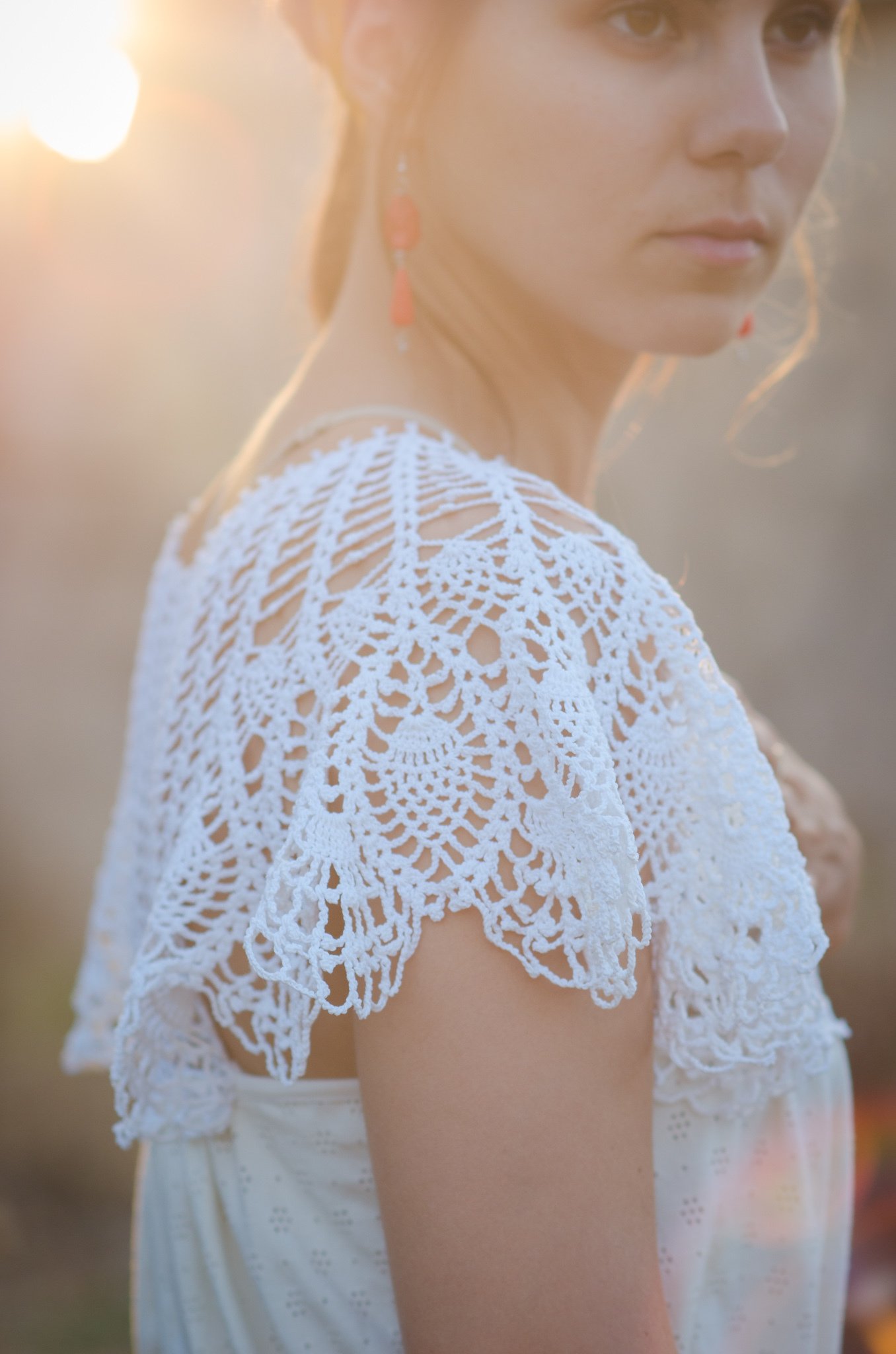 A close up of a woman wearing a white crocheted top.