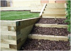 Raised grassed are with wooden steps and bark chippings down - child friendly space