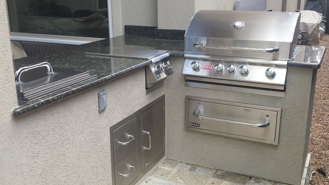 A stainless steel grill is sitting on top of a granite counter top.