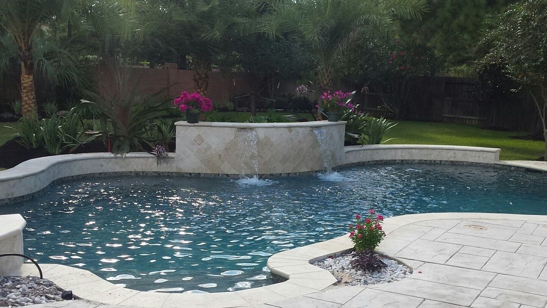 A large swimming pool with a waterfall in the backyard.