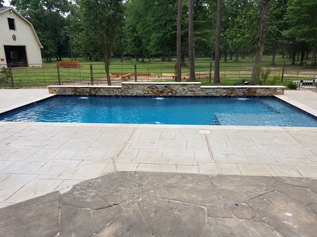 A large swimming pool with a white barn in the background
