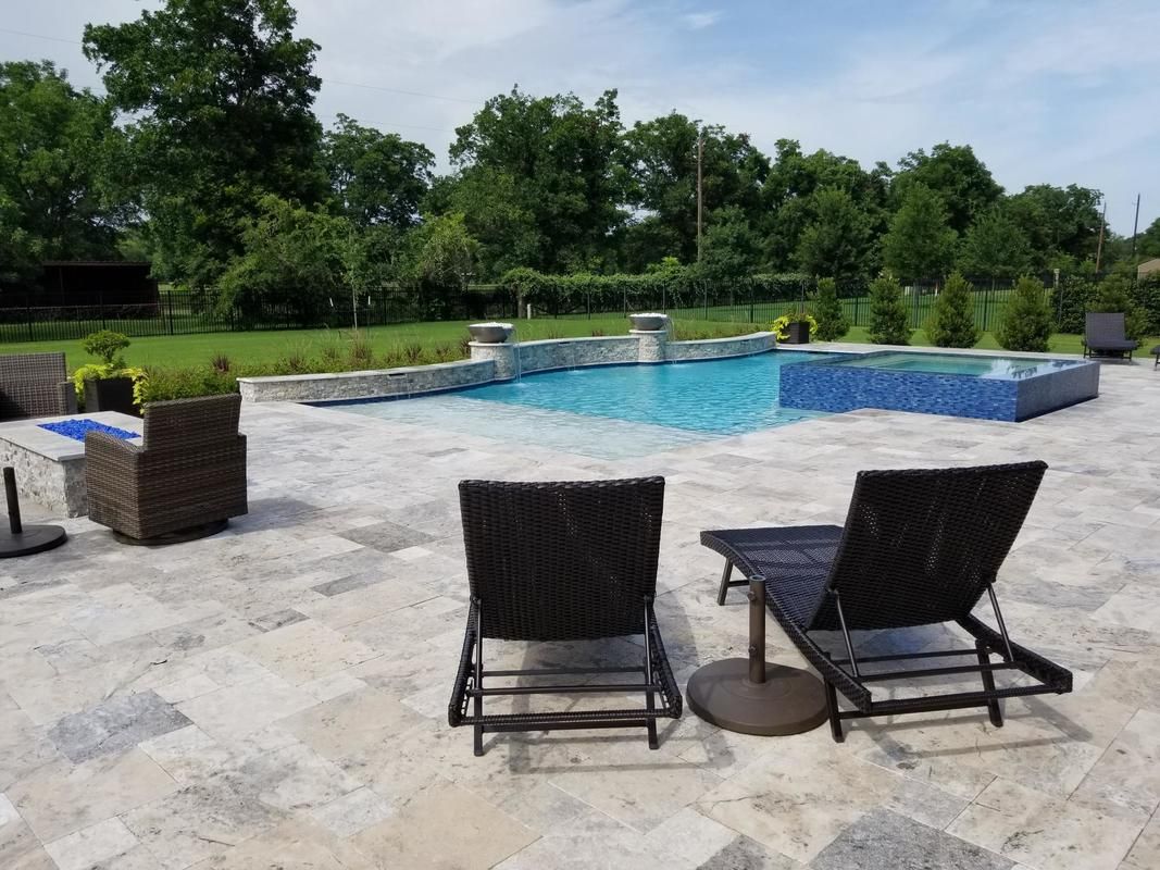 Two lounge chairs are sitting on a patio next to a large swimming pool.