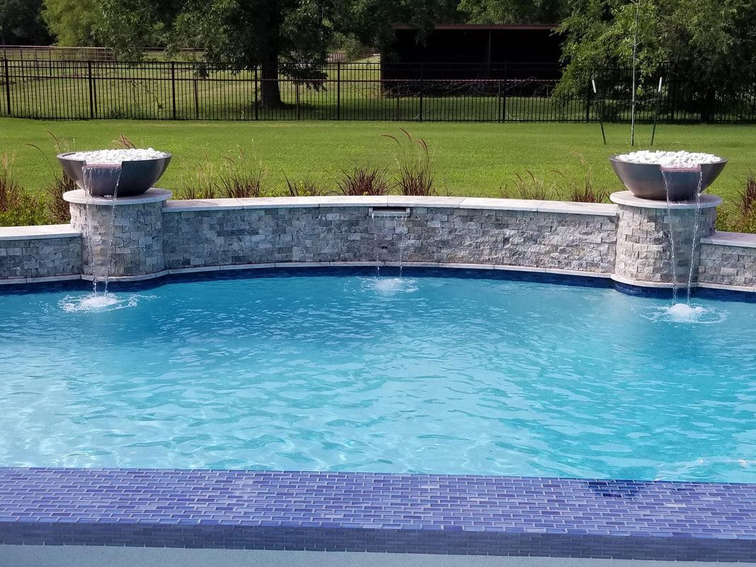 A large swimming pool with a waterfall in the middle of it.