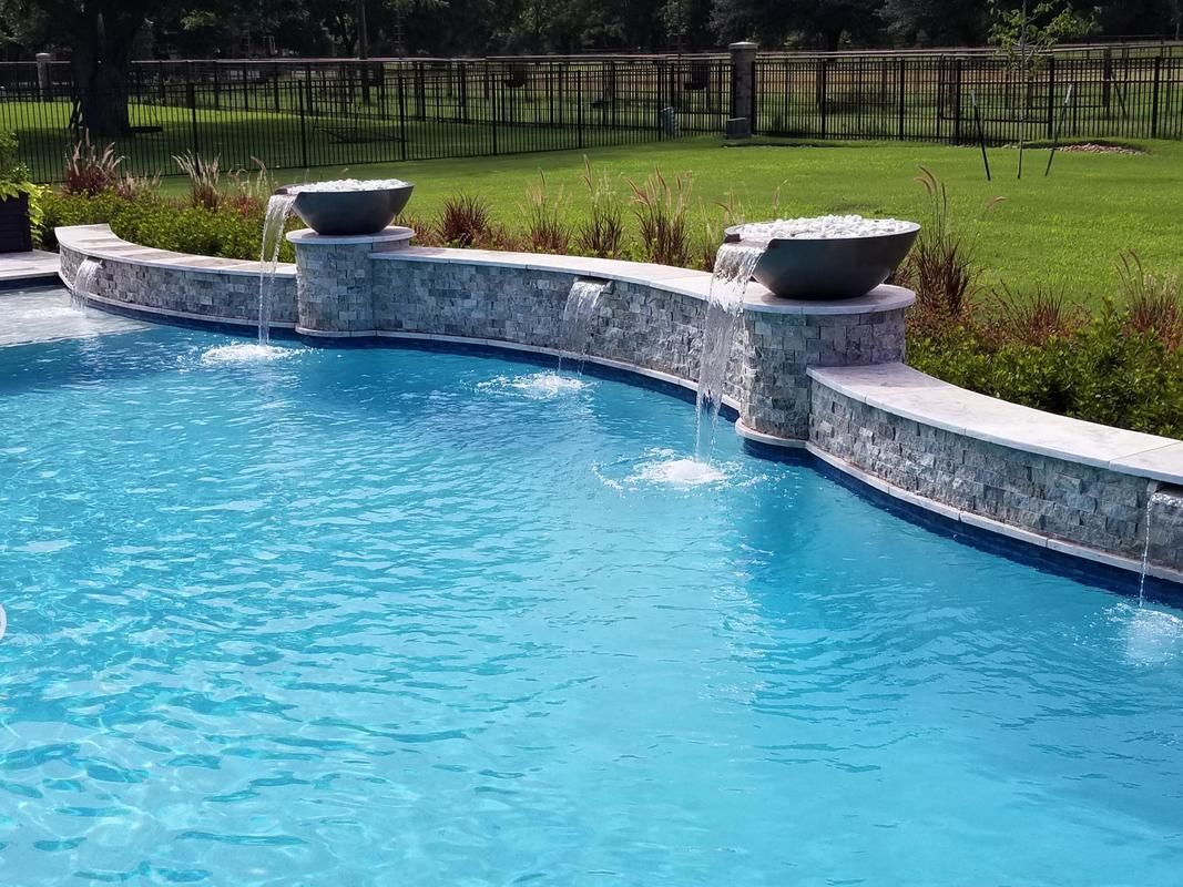 A large swimming pool with a waterfall in the middle of it.