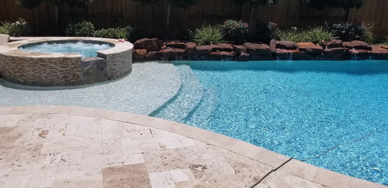 A large swimming pool with a hot tub next to it.