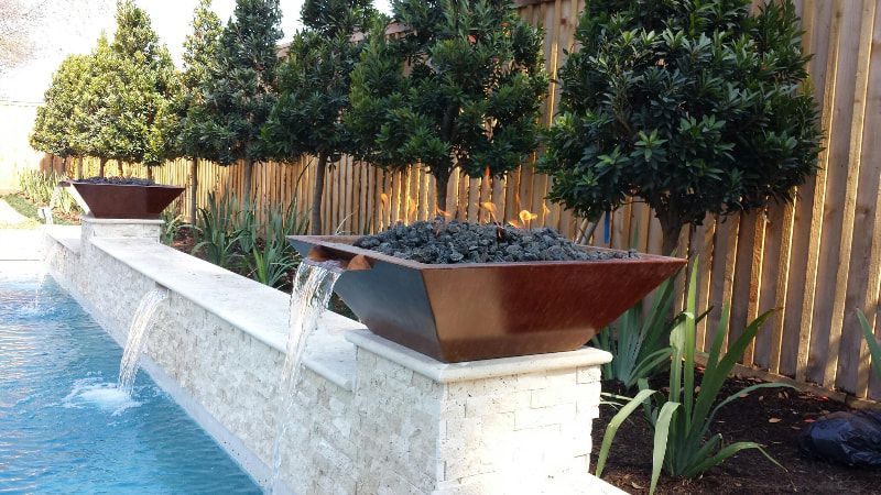 A swimming pool with a waterfall and trees in the background.