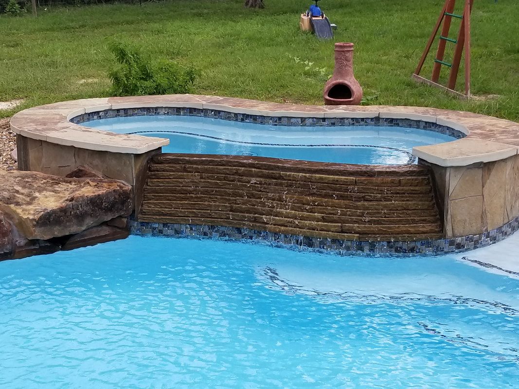 A swimming pool with a hot tub in the middle of it.