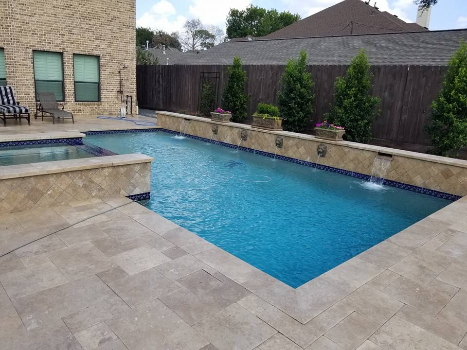A large swimming pool is in the backyard of a house.