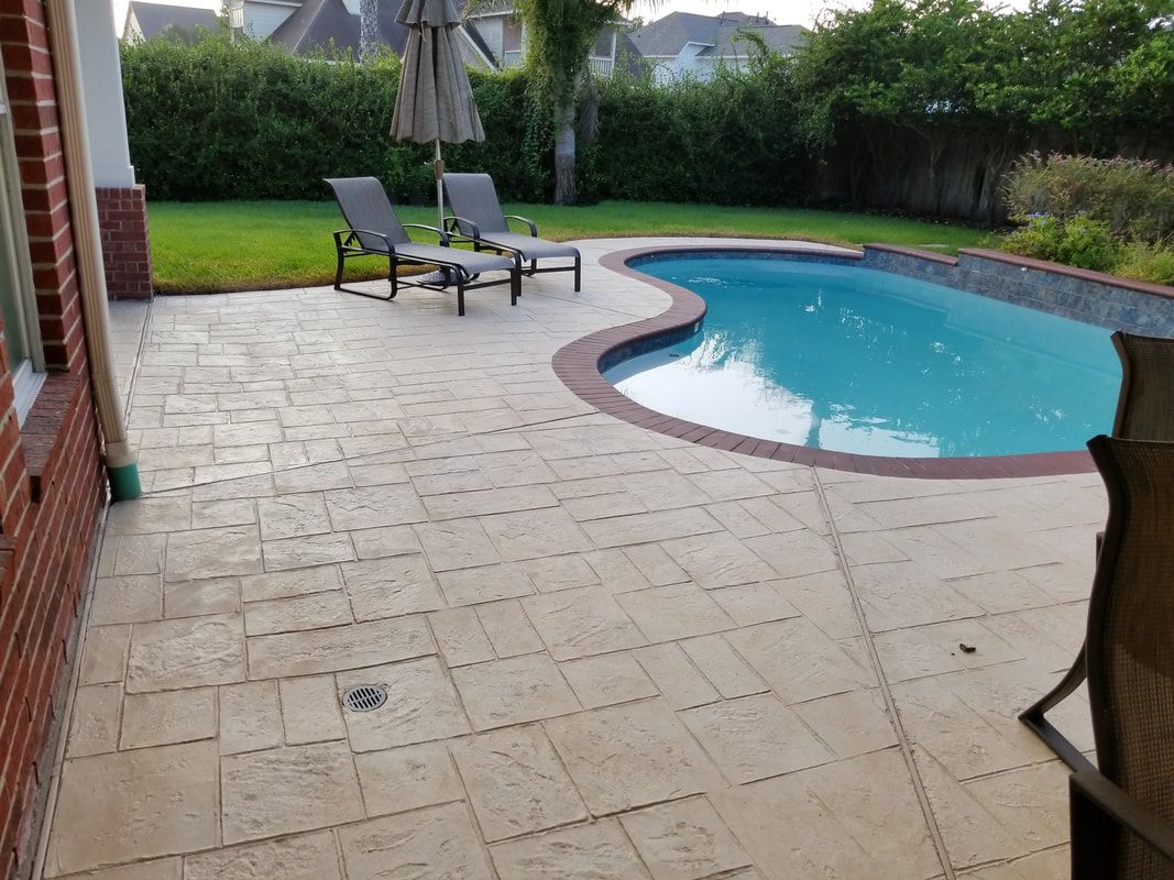A large swimming pool is surrounded by a patio with chairs and umbrellas.