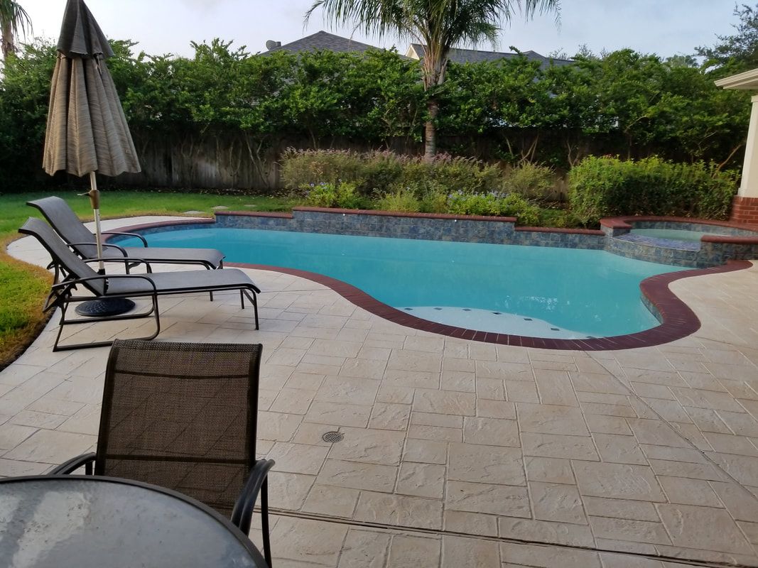 A large swimming pool is surrounded by chairs and umbrellas on a patio.