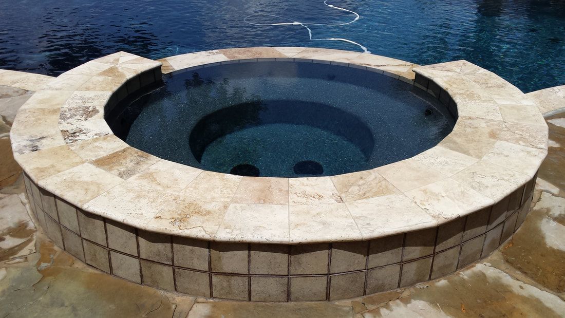A round hot tub is sitting next to a swimming pool.