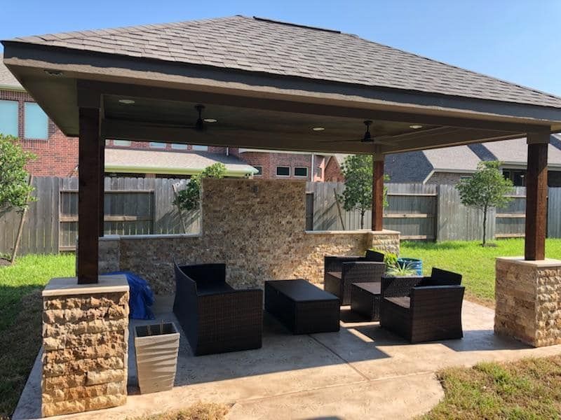 There is a gazebo in the backyard with furniture underneath it.