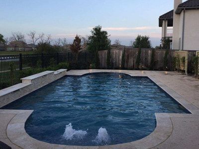 There is a large swimming pool in the backyard of a house.