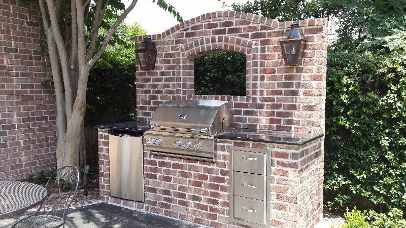 A brick wall with a grill and a mirror on it