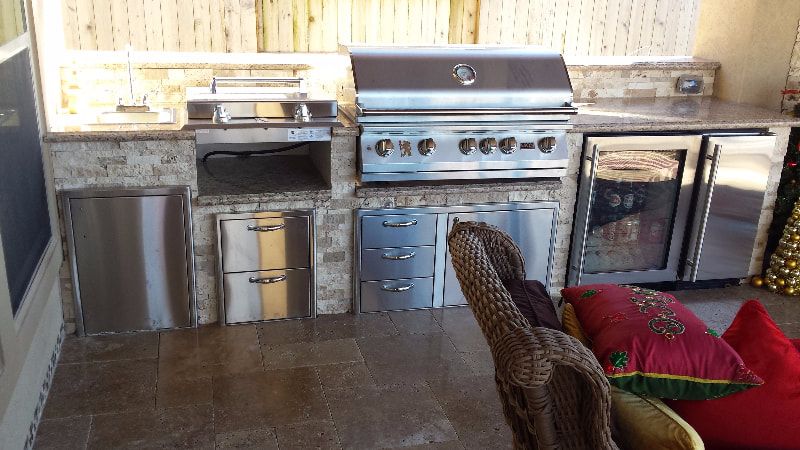 A kitchen with a stainless steel grill and a wicker chair.