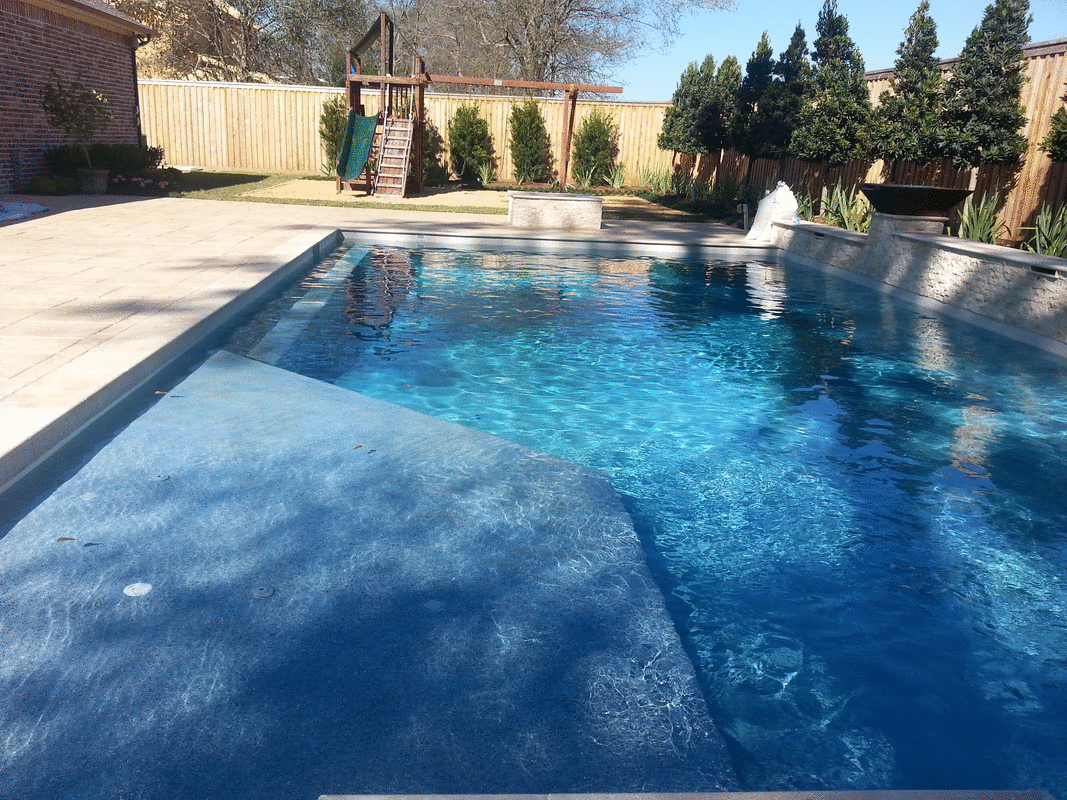 A large swimming pool with a waterfall in the backyard