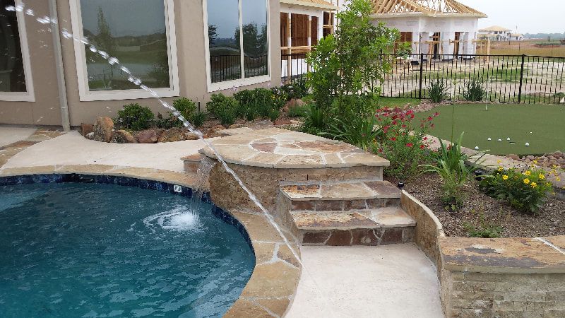 A swimming pool with a fountain in the middle of it and stairs leading to it.