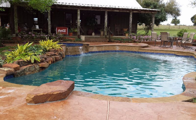 A large swimming pool is in front of a house.