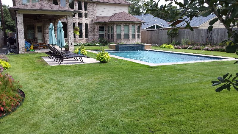 There is a large swimming pool in the backyard of a house.