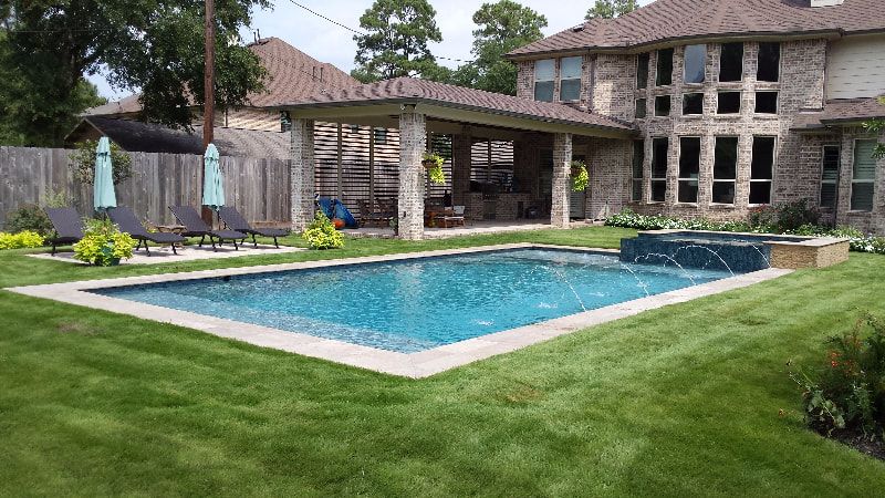 There is a large swimming pool in the backyard of a house.