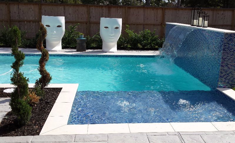 A large swimming pool with a waterfall in the backyard