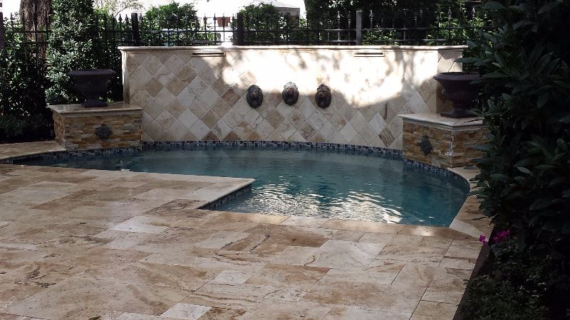 A large swimming pool is surrounded by a tiled patio.