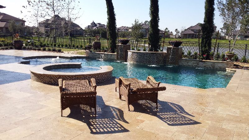 Two chairs are sitting on a patio next to a large swimming pool.