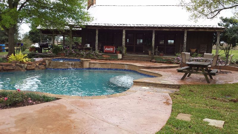 A house with a swimming pool and a picnic table in front of it.