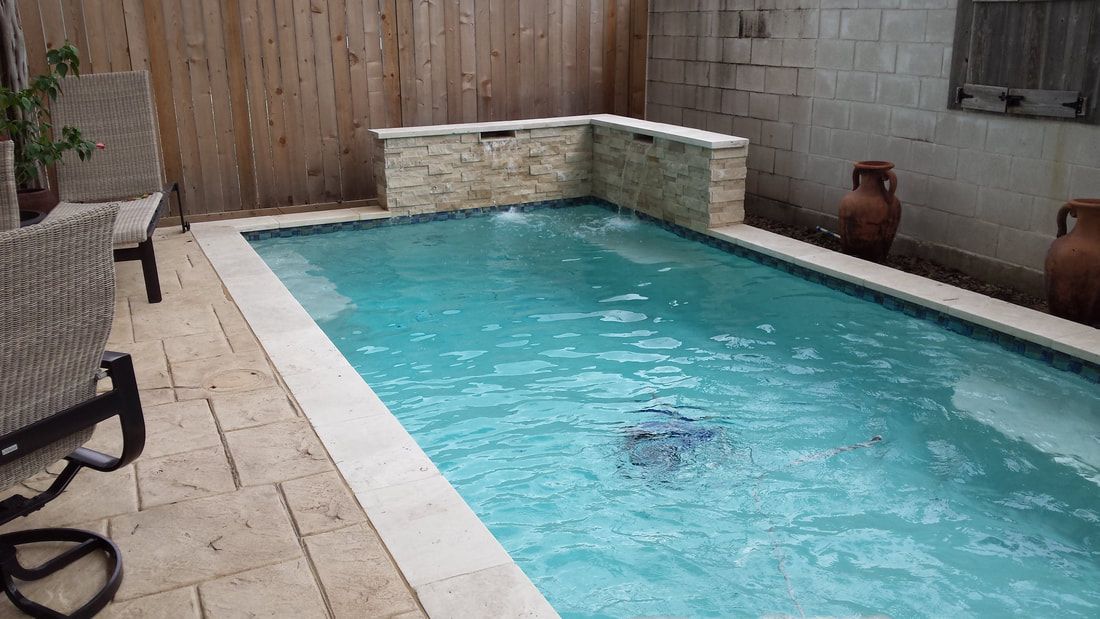 A small swimming pool is surrounded by a wooden fence and chairs.