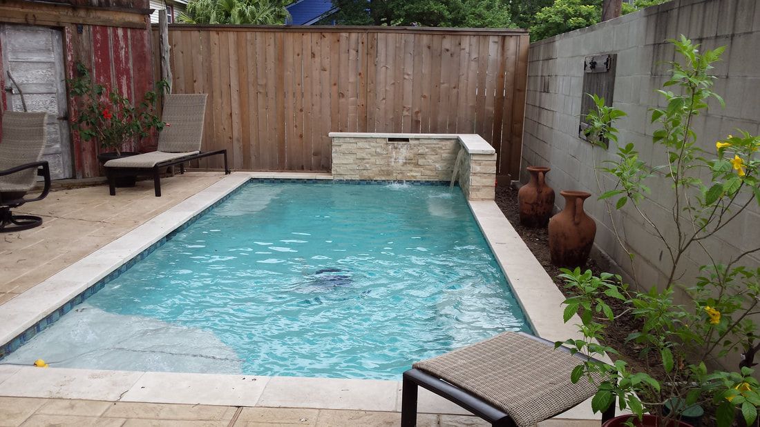 A small swimming pool is surrounded by a wooden fence and chairs.