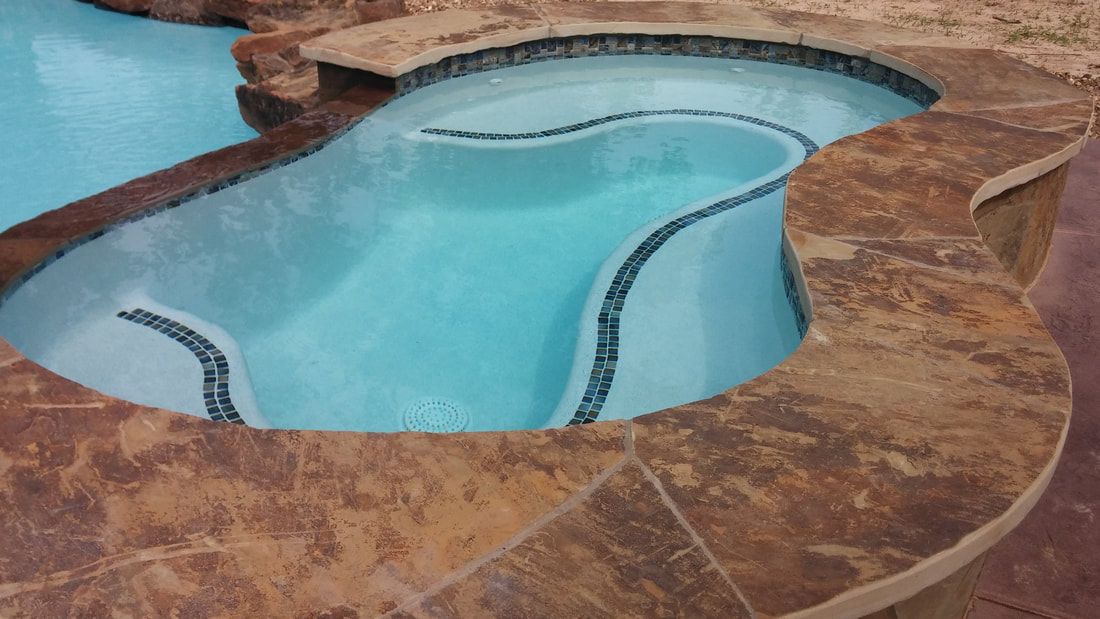 A swimming pool with a hot tub in the middle of it.