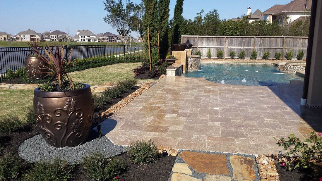 A patio with a fountain and a pool in the background.