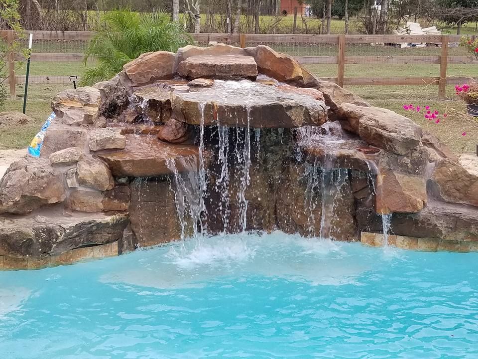 There is a waterfall in the middle of a swimming pool.