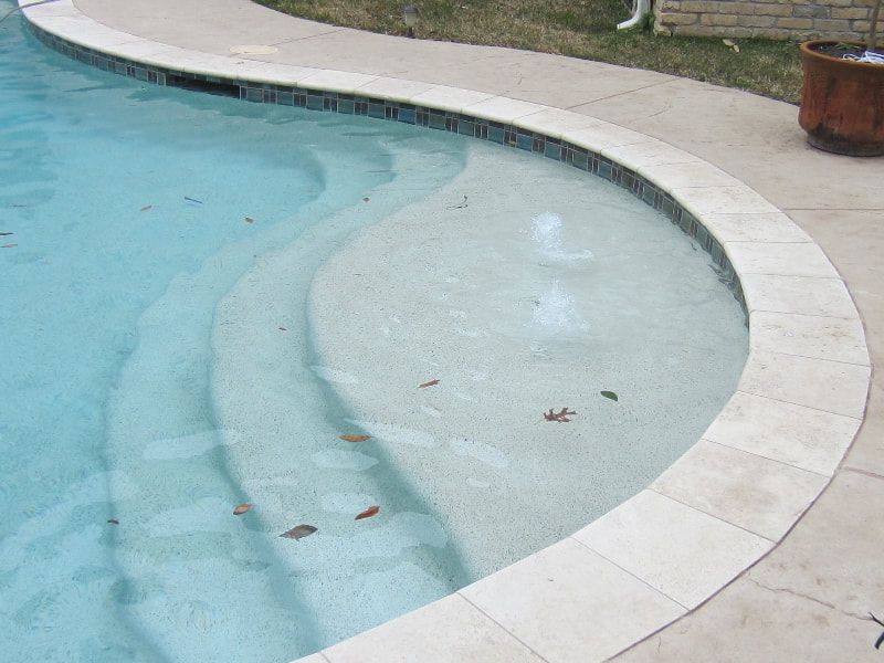 A curved edge of a swimming pool with steps