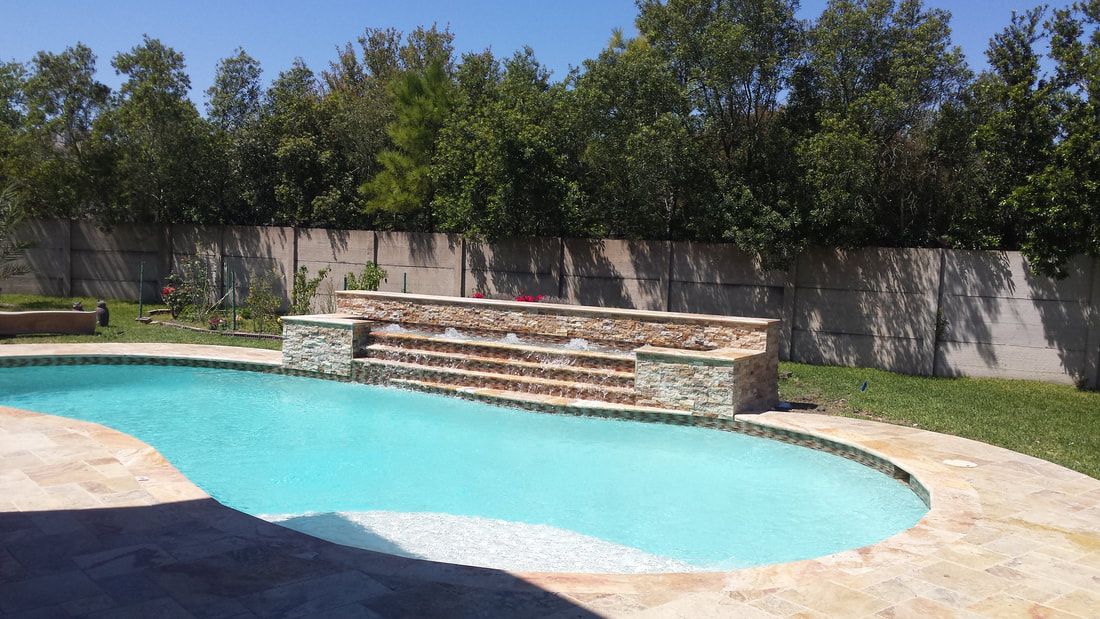 A large swimming pool with a waterfall in the backyard.