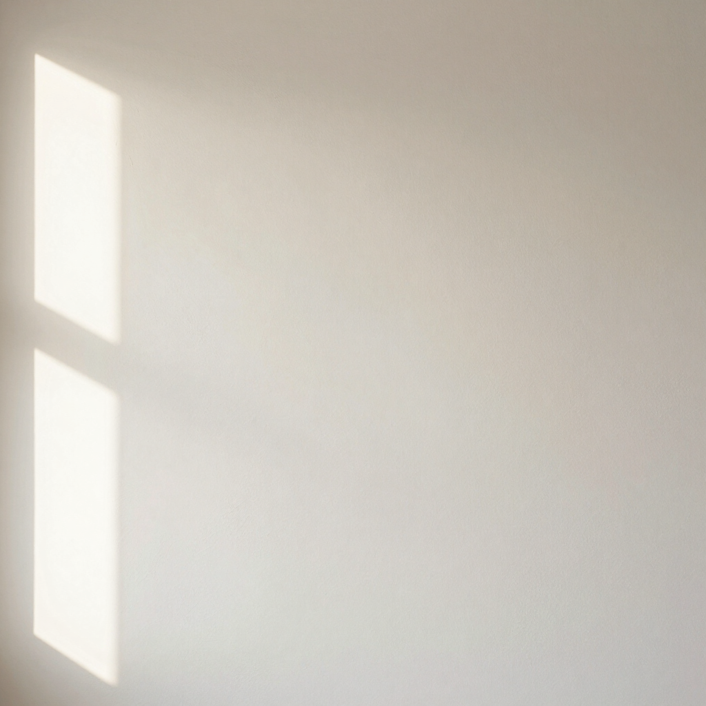 Close-up of matte warm off-white plastered wall with a sliver of window light