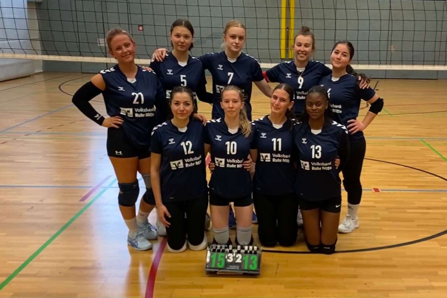 Volleyballteam der Damen I posiert in dunkelblauen Trikots in einer Turnhalle.