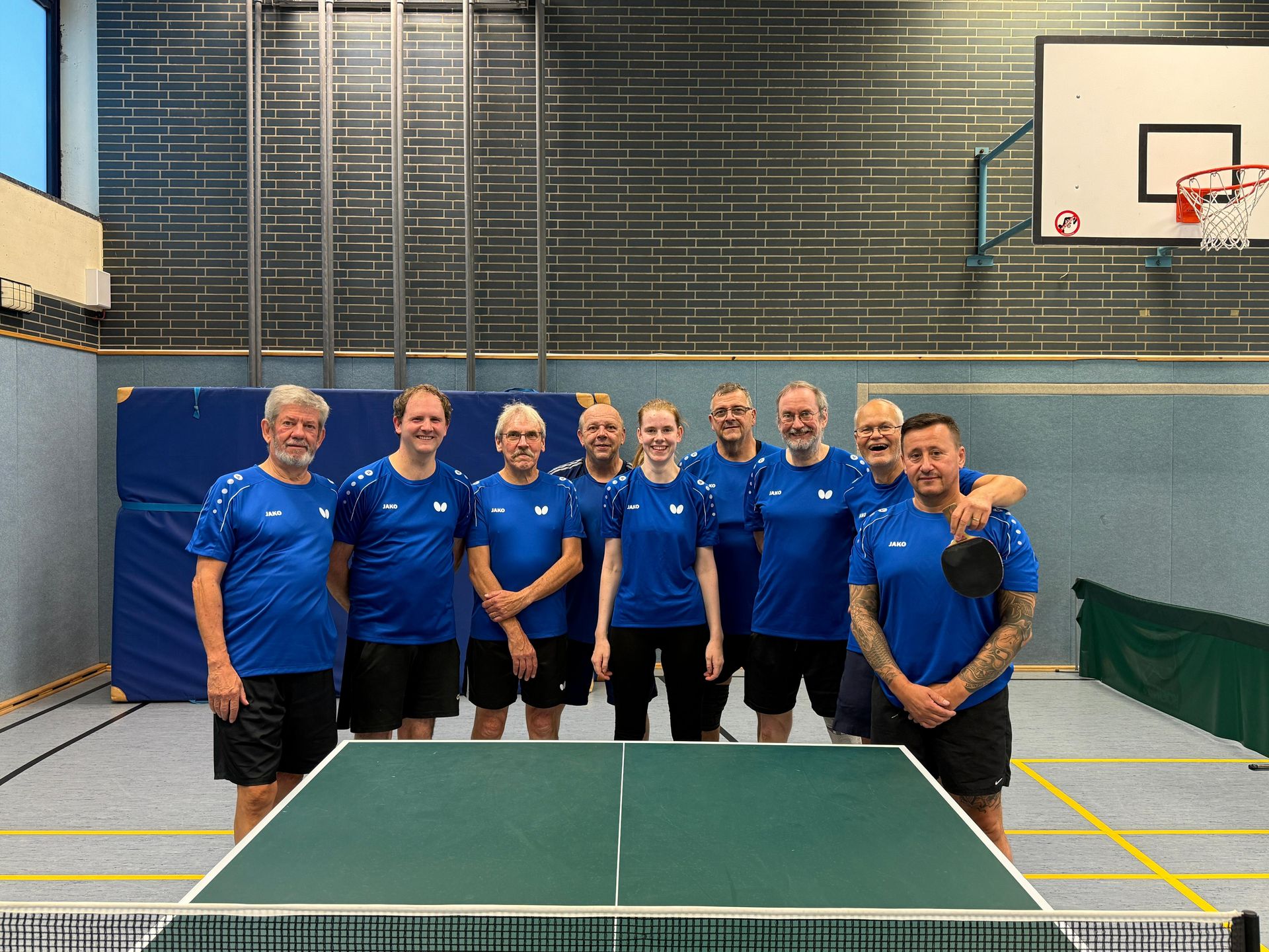 Das Team der Tischtennis-Abteilung des Post SV Buer steht vor einer Tischtennis-Platte