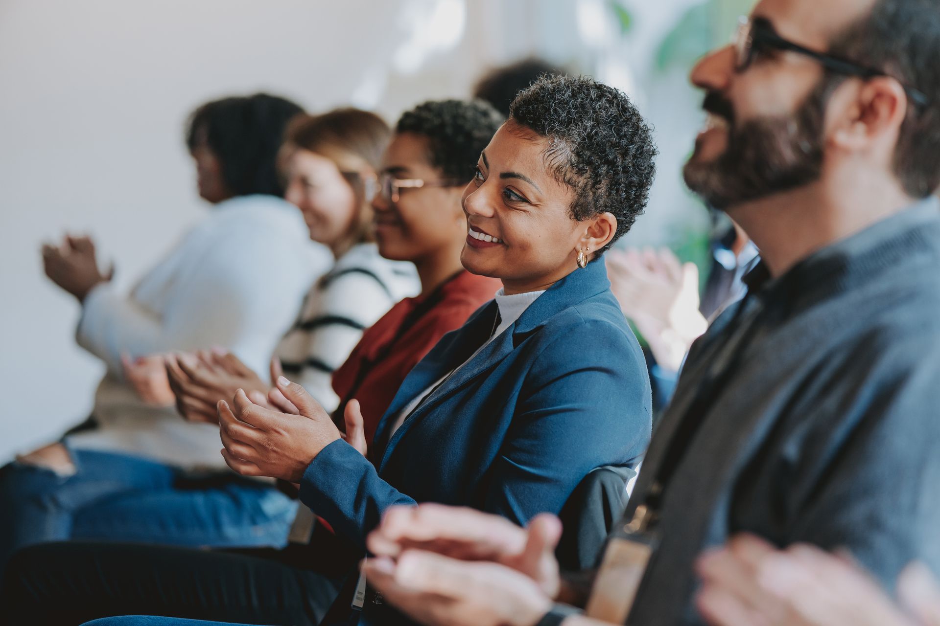 A group of people are sitting in a row clapping their hands.
