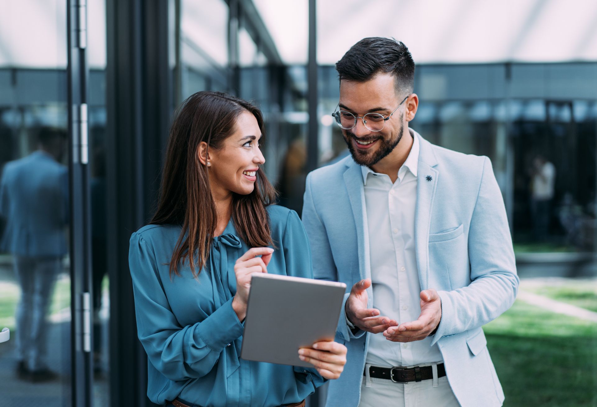 A man and a woman are standing next to each other looking at a tablet.