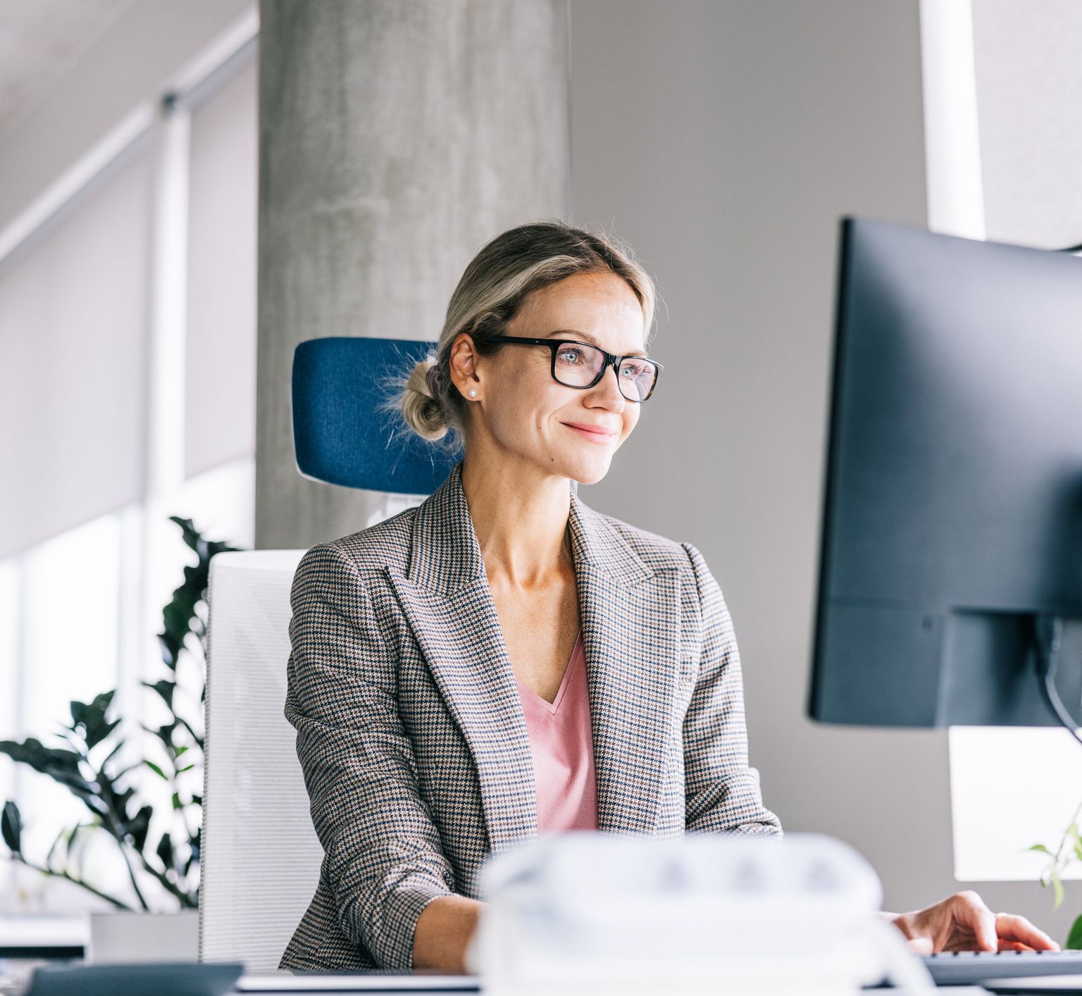 A woman is sitting at a desk in front of a computer.