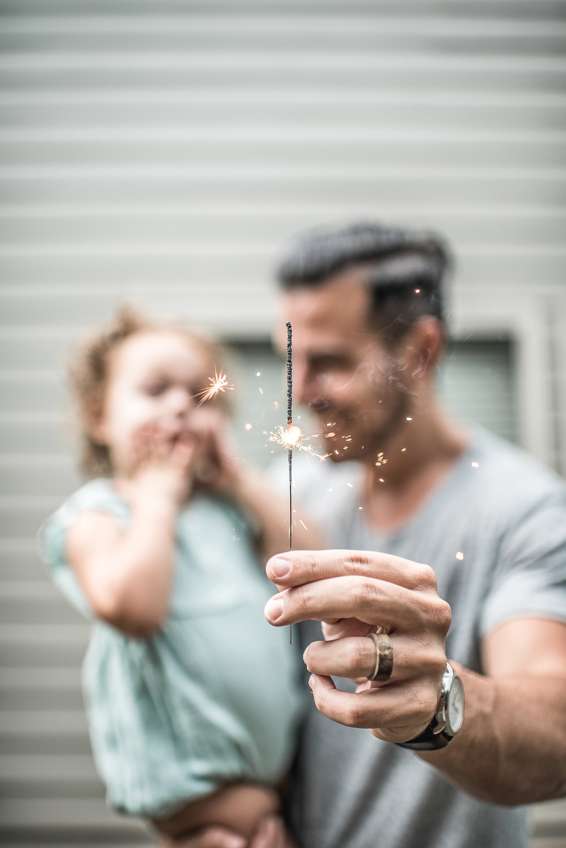 Father, child playing with sparkler in front of home, symbolizing community by Authority Property Management.