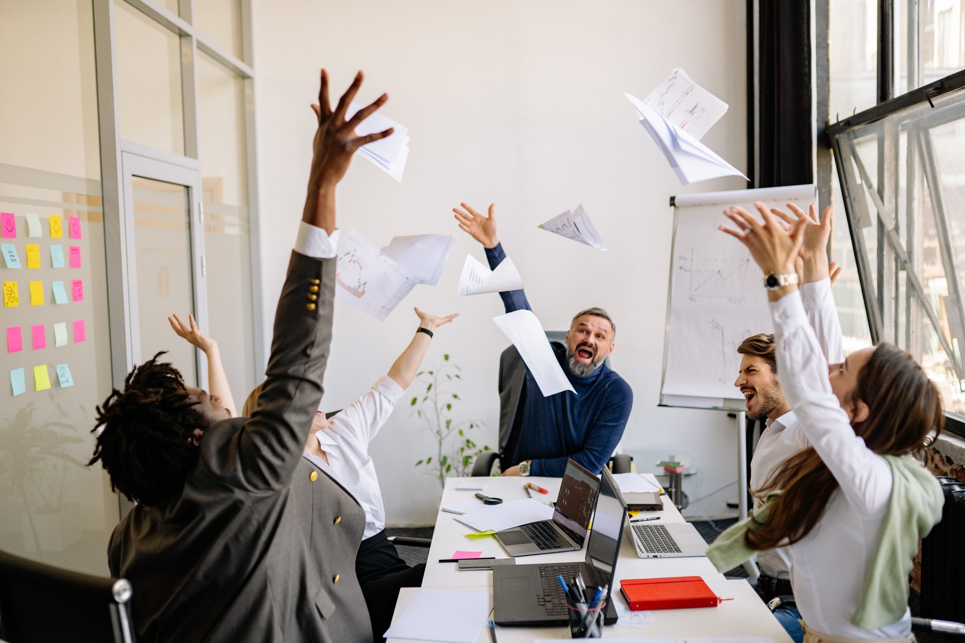 A group of people are throwing papers in the air in an office.