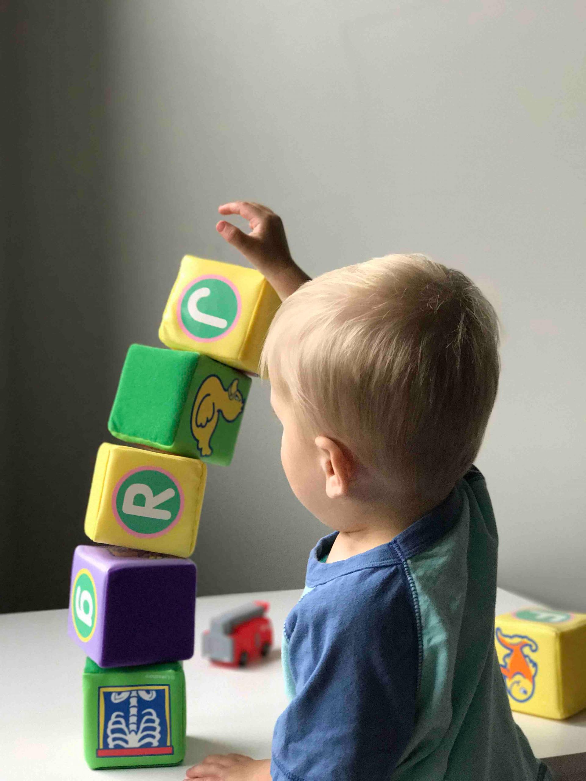 A young boy is stacking blocks on top of each other on a table.